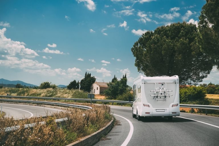 white-caravan-motorhome-car-goes-on-highway-road-N8Y2FQL